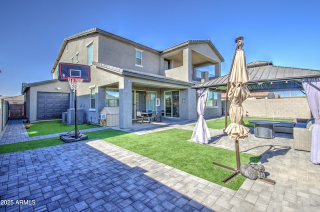 rear view of house featuring a balcony, a yard, central AC unit, and a patio