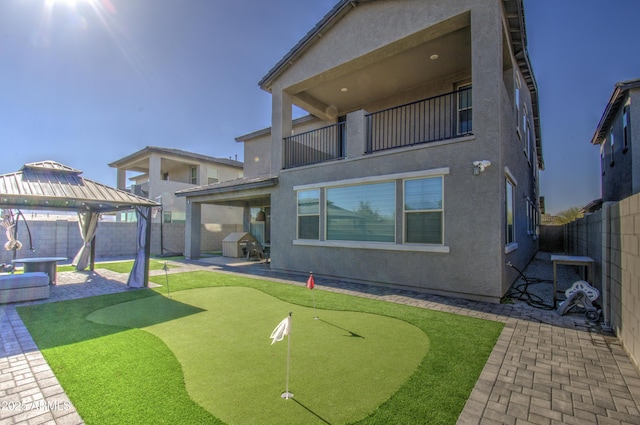 rear view of property with a gazebo, a balcony, and a patio