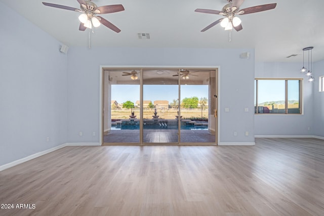 unfurnished room featuring plenty of natural light, ceiling fan, and wood-type flooring