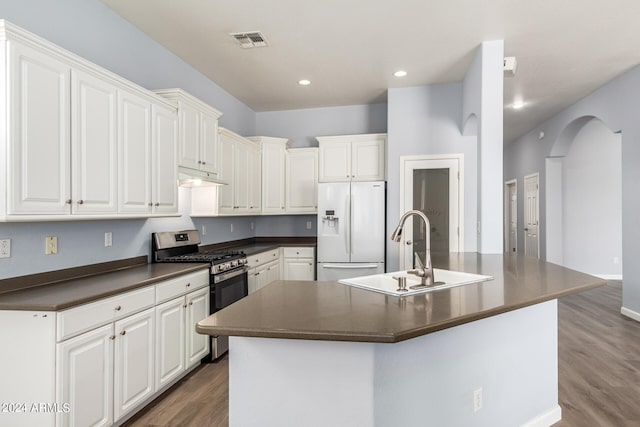 kitchen with white fridge with ice dispenser, a center island with sink, stainless steel range with gas stovetop, and wood-type flooring