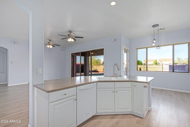 kitchen with ceiling fan, light wood-type flooring, hanging light fixtures, sink, and white cabinets