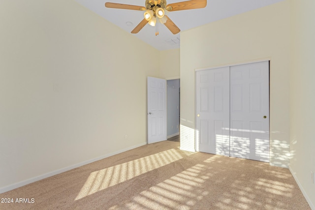 unfurnished bedroom with high vaulted ceiling, carpet flooring, a closet, and ceiling fan