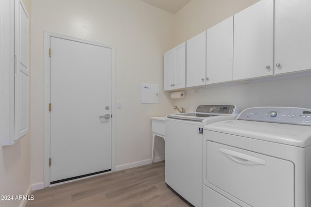 washroom featuring cabinets, light hardwood / wood-style floors, and washing machine and dryer