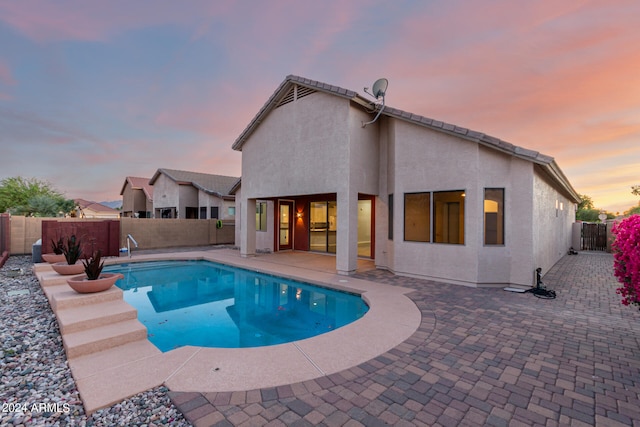 pool at dusk featuring a patio