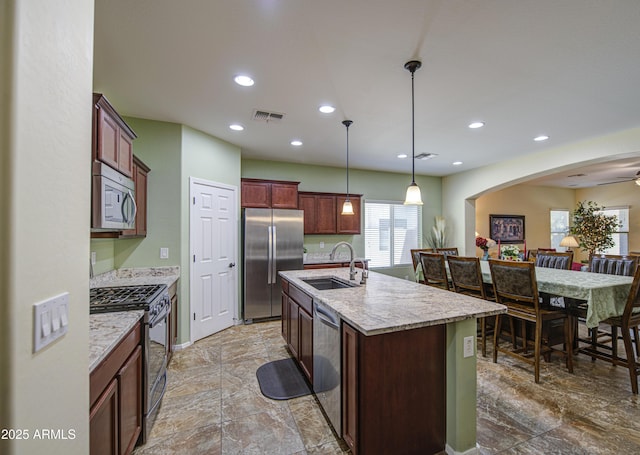 6554 W Rushmore Way, Florence, AZ 85132 - kitchen with appliances with stainless steel finishes, recessed lighting, a center island with sink, decorative light fixtures, and light stone countertops