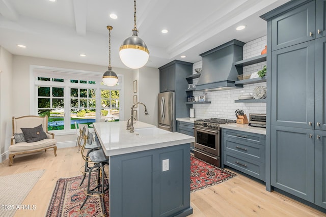 kitchen featuring sink, custom exhaust hood, an island with sink, pendant lighting, and stainless steel appliances