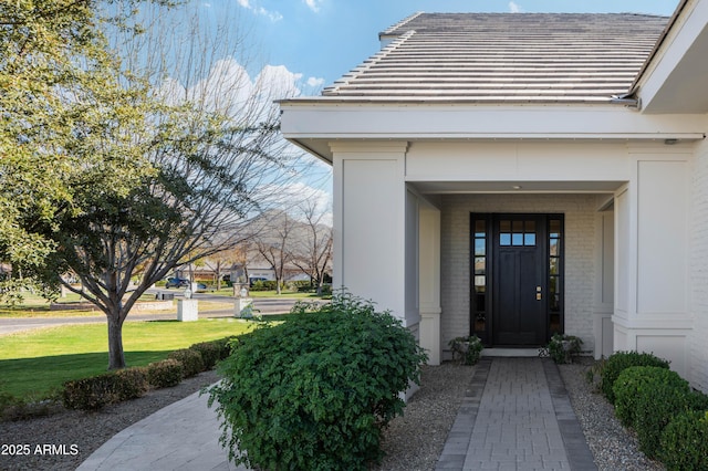 view of exterior entry featuring a lawn