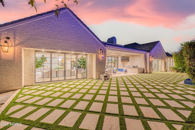 back house at dusk featuring a patio