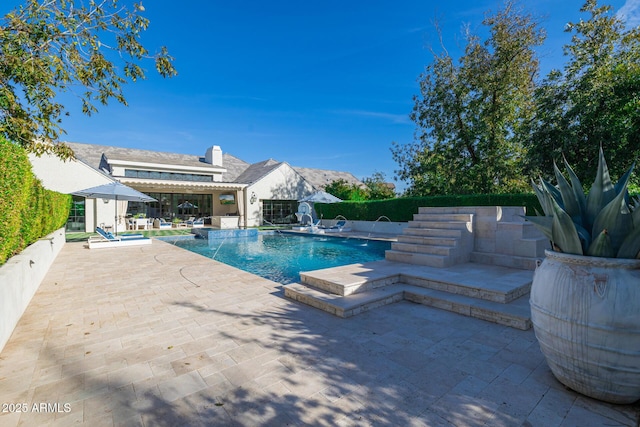 view of swimming pool with pool water feature and a patio area