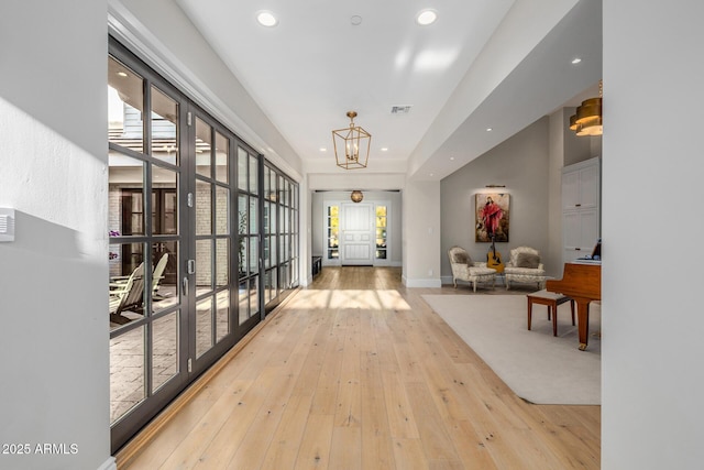 corridor with a chandelier and light hardwood / wood-style floors