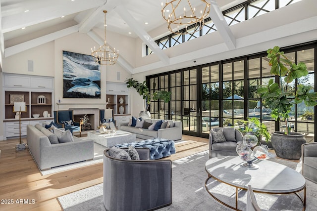 living room featuring beam ceiling, a wealth of natural light, an inviting chandelier, and light hardwood / wood-style floors