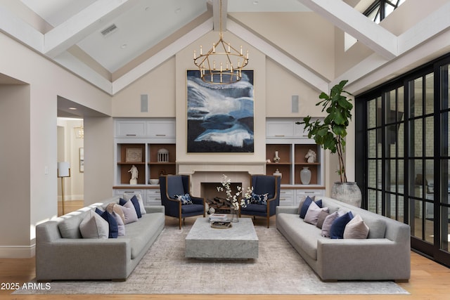 living room with a notable chandelier, hardwood / wood-style floors, a premium fireplace, and beamed ceiling