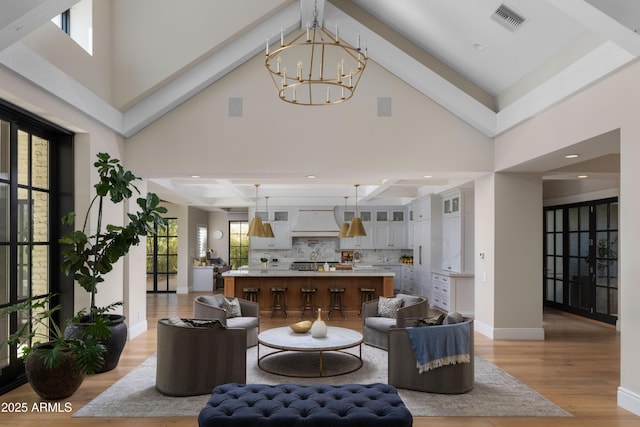 living room featuring a notable chandelier, light hardwood / wood-style flooring, and a high ceiling