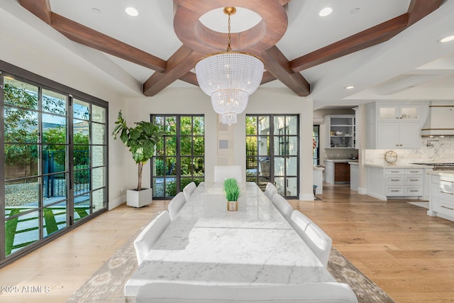 interior space featuring beam ceiling, an inviting chandelier, and light hardwood / wood-style flooring