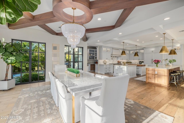 dining room with beamed ceiling, coffered ceiling, a notable chandelier, and light hardwood / wood-style flooring