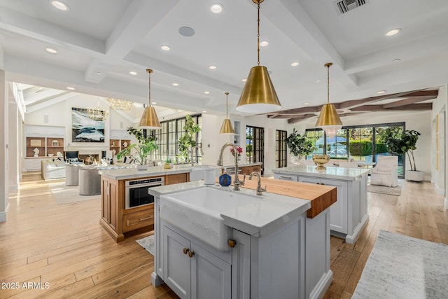 kitchen with a healthy amount of sunlight, decorative light fixtures, stainless steel oven, and a spacious island