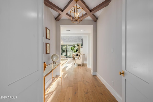 hall featuring coffered ceiling, light hardwood / wood-style floors, a chandelier, and beamed ceiling