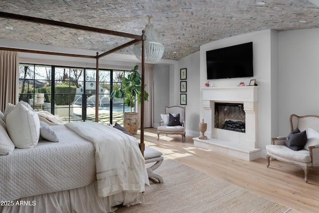 bedroom with brick ceiling, access to outside, and light wood-type flooring