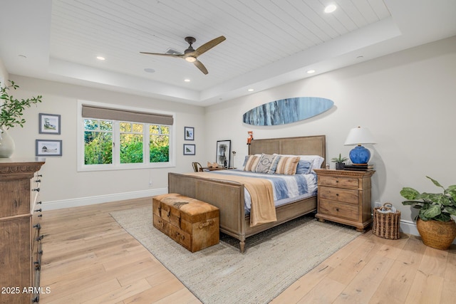 bedroom with ceiling fan, wooden ceiling, light hardwood / wood-style floors, and a tray ceiling