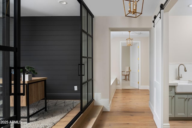 hallway featuring a barn door, light hardwood / wood-style floors, and sink