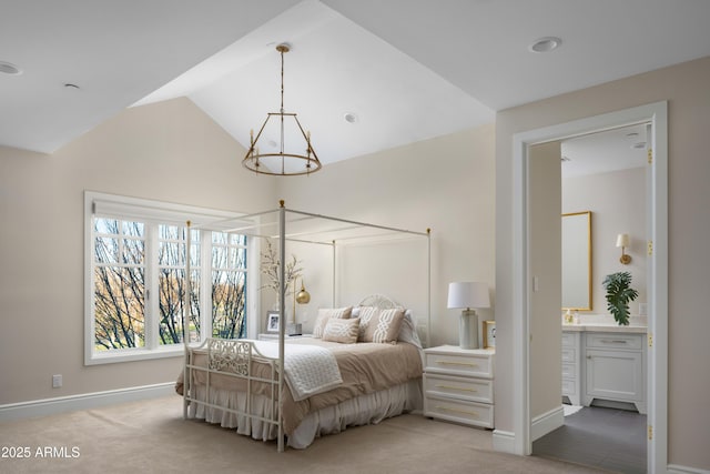 carpeted bedroom with ensuite bath, lofted ceiling, and a chandelier