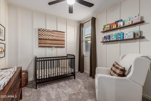 bedroom with ceiling fan, light colored carpet, and a nursery area