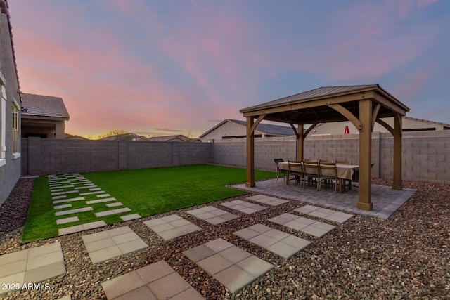 yard at dusk featuring a gazebo and a patio