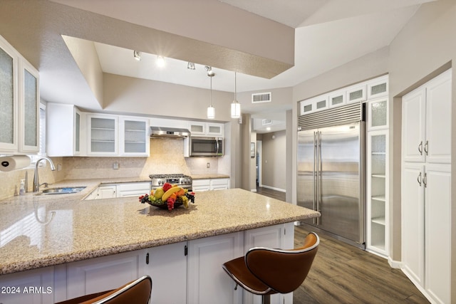 kitchen with pendant lighting, dark hardwood / wood-style flooring, a breakfast bar, white cabinets, and premium appliances