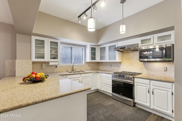 kitchen featuring exhaust hood, light stone countertops, hanging light fixtures, stainless steel appliances, and white cabinetry