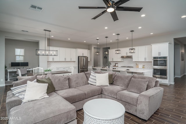 12702 W Sierra Vista Dr, Glendale, AZ 85307 - living room with visible vents, baseboards, ceiling fan with notable chandelier, wood finish floors, and recessed lighting