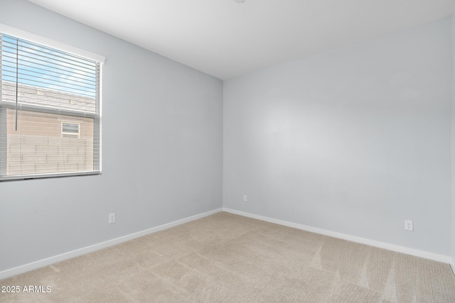 unfurnished room with light colored carpet and baseboards