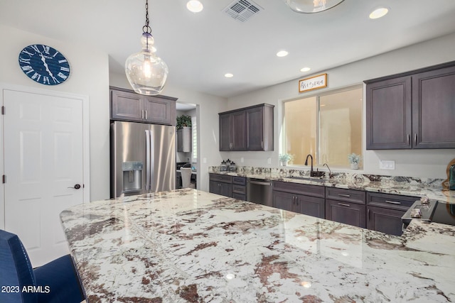 kitchen with pendant lighting, sink, light stone countertops, appliances with stainless steel finishes, and dark brown cabinetry