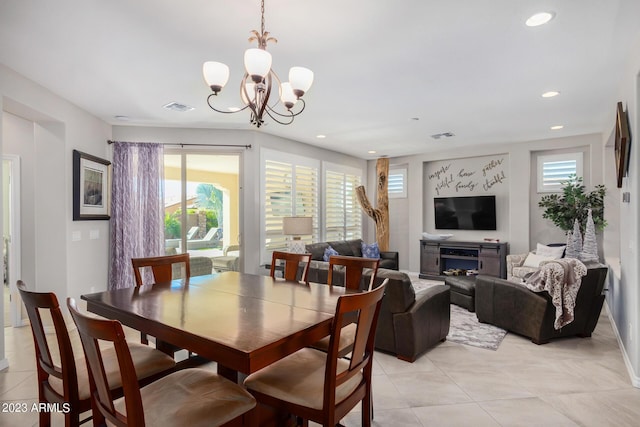 tiled dining space with a fireplace and a chandelier