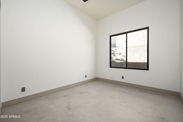 spare room featuring a ceiling fan, concrete floors, and baseboards