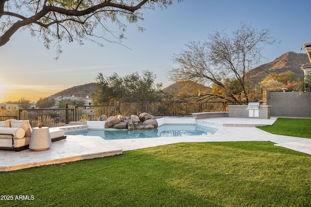 view of swimming pool featuring a fenced backyard, a mountain view, area for grilling, and a lawn