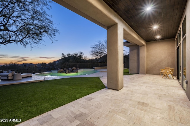 patio terrace at dusk featuring a fenced in pool, a yard, and a hot tub