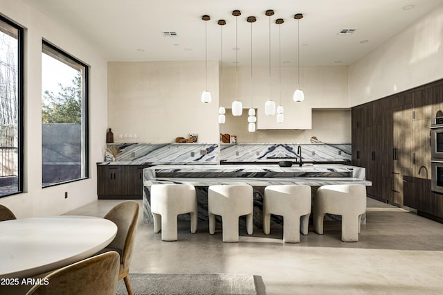 kitchen with finished concrete flooring, modern cabinets, visible vents, and dark brown cabinetry