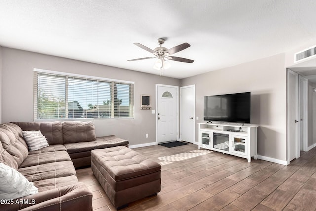 living room featuring a textured ceiling, wood-type flooring, and ceiling fan