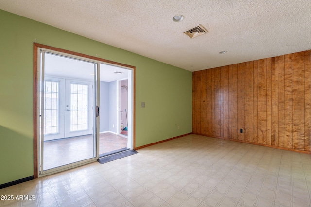 1654 E 2nd St, Mesa, AZ 85203 - empty room featuring wood walls, light flooring, baseboards, french doors, and a textured ceiling