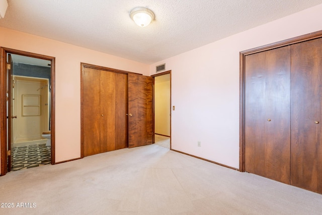 1654 E 2nd St, Mesa, AZ 85203 - unfurnished bedroom with two closets, light colored carpet, baseboards, ensuite bathroom, and a textured ceiling