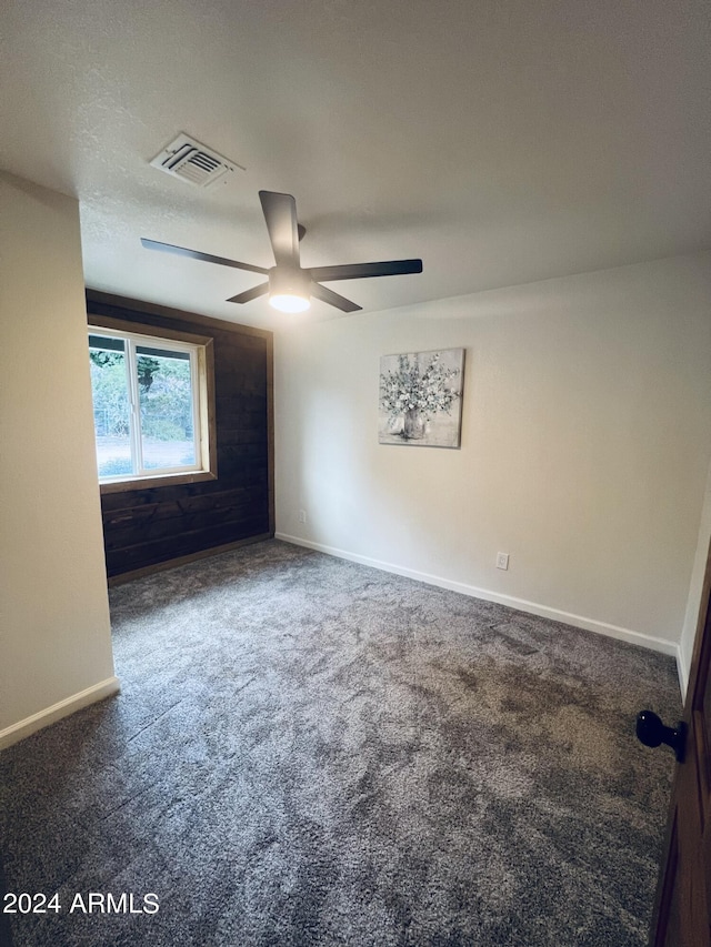 spare room featuring dark colored carpet and ceiling fan