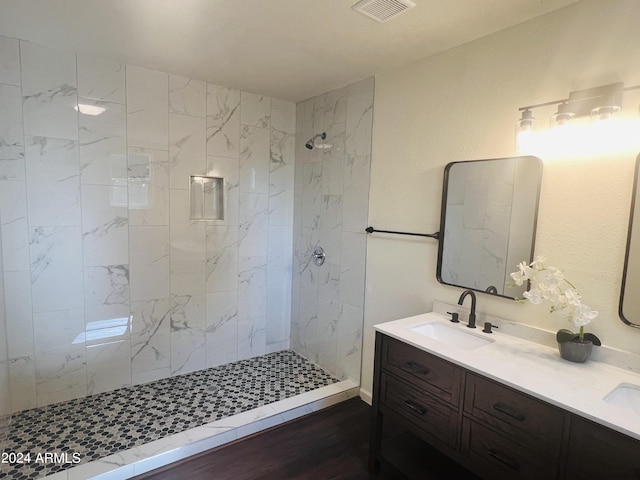 bathroom featuring a tile shower, wood-type flooring, and vanity