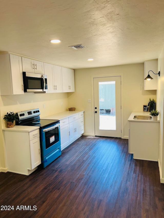 kitchen with appliances with stainless steel finishes, dark hardwood / wood-style flooring, white cabinets, and sink