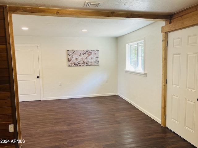 unfurnished room with beam ceiling and dark hardwood / wood-style floors