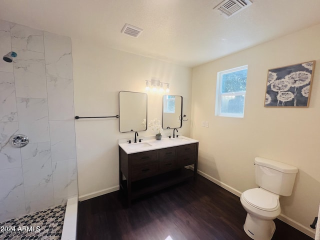 bathroom with toilet, a tile shower, hardwood / wood-style flooring, and vanity