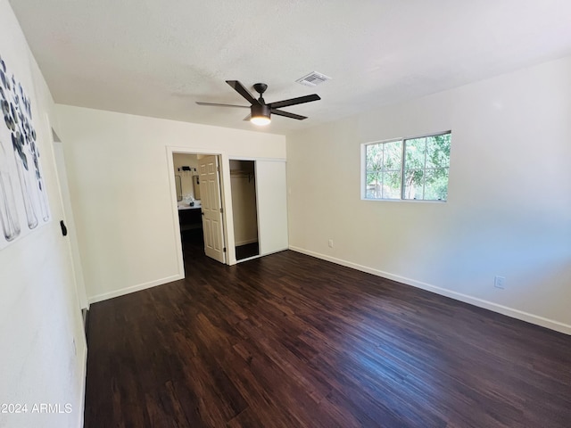 unfurnished bedroom with ceiling fan, a closet, dark hardwood / wood-style floors, and a textured ceiling