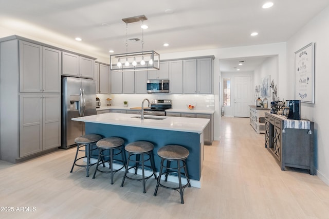 24638 N 144th Ave, Surprise, AZ 85387 - kitchen featuring appliances with stainless steel finishes, a sink, a breakfast bar, light countertops, and gray cabinets