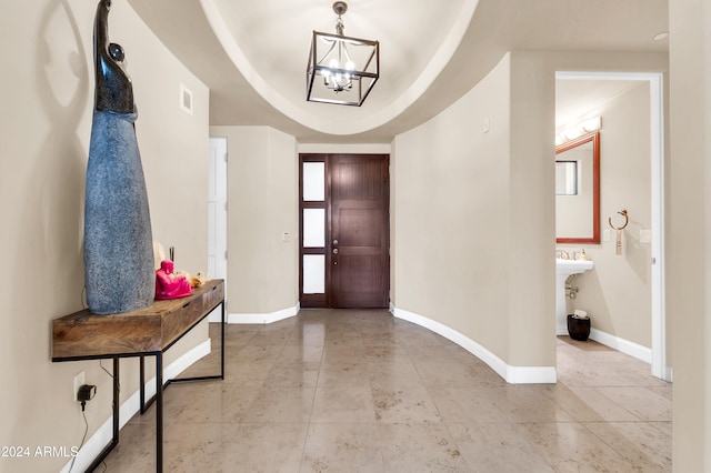 foyer entrance with an inviting chandelier and a raised ceiling