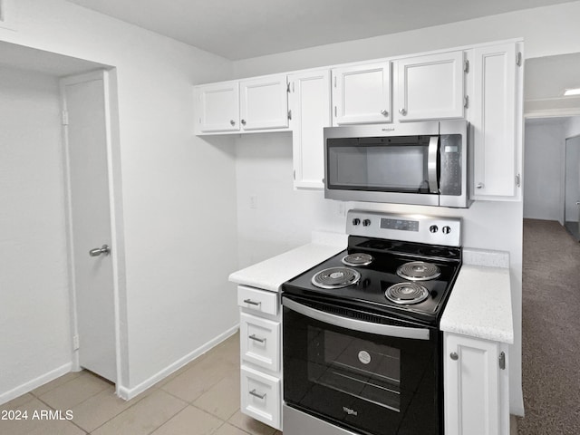 kitchen featuring appliances with stainless steel finishes, light tile patterned flooring, and white cabinets