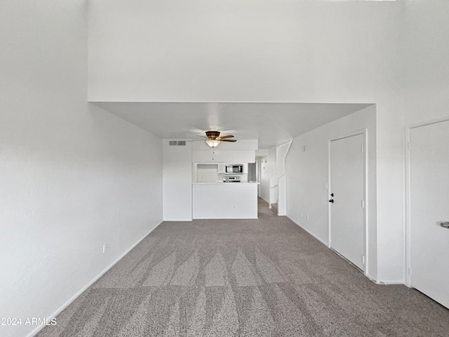 unfurnished living room featuring ceiling fan and carpet floors